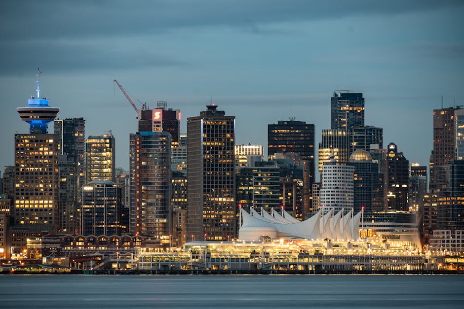 Twilight view of Vancouver skyline featuring iconic Canada Place and skyscrapers reflecting city lights.